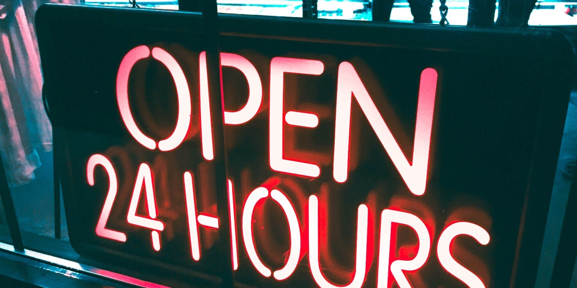 A bright neon shop sign stating: 'Open 24 hours'