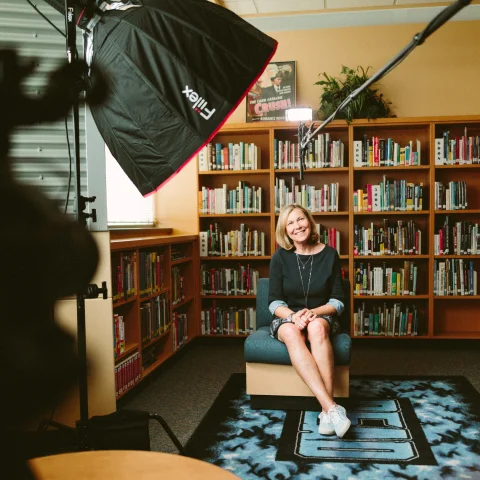 Person being interviewed in front of bookcase with extra lights