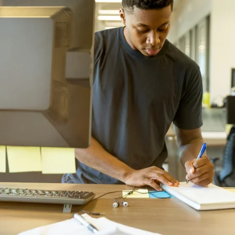 Person making notes in notebook and post-its