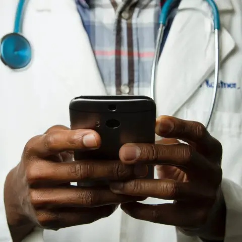 A doctor holding a phone to look something up