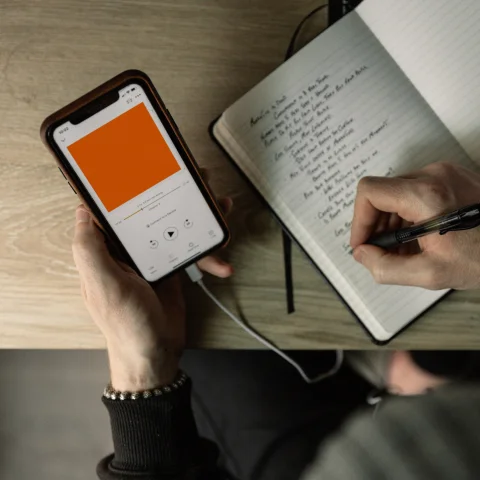 Person making notes whilst listening to podcast